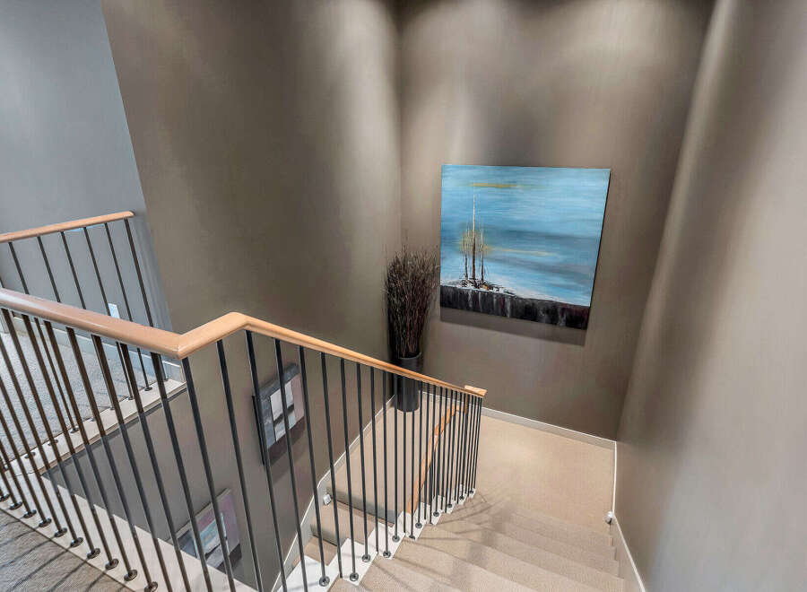 Modern staircase with sleek metal balusters and light wood handrail adds a touch of elegance to this home.
