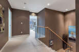 This stunning hallway boasts a modern design with dark brown walls, plush carpeting, and a sleek metal and wood staircase.