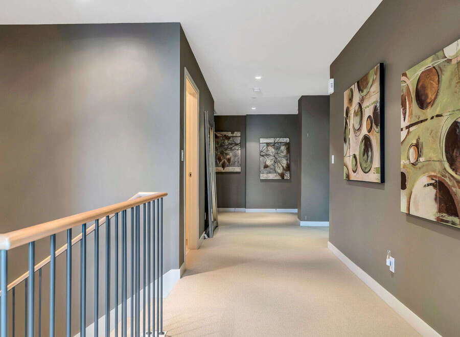 This stunning hallway boasts a neutral color palette, complemented by modern artwork and a sleek metal railing.