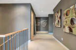 This stunning hallway boasts a neutral color palette, complemented by modern artwork and a sleek metal railing.