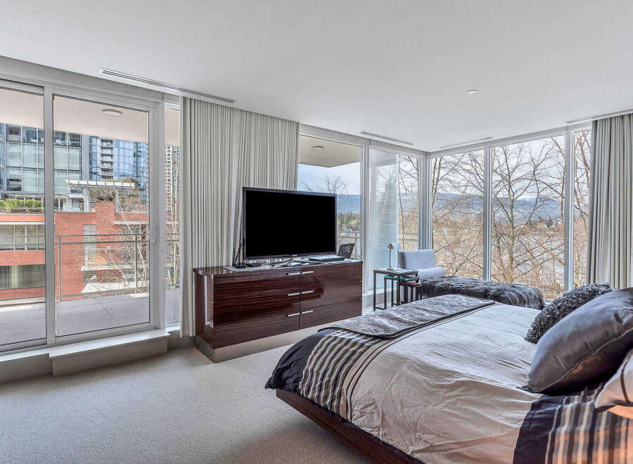Luxurious bedroom with floor-to-ceiling windows offering stunning city and nature views.