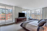 Luxurious bedroom with floor-to-ceiling windows offering stunning city and nature views.