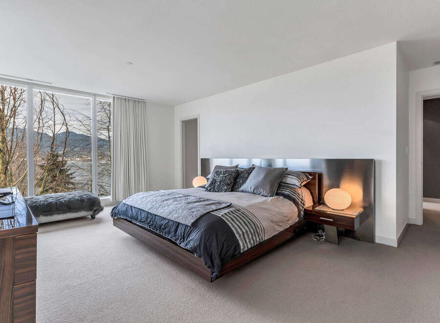 This luxurious bedroom boasts stunning views of mountains and water, thanks to its large windows and serene location.