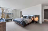 This luxurious bedroom boasts stunning views of mountains and water, thanks to its large windows and serene location.