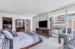 Luxurious bedroom with floor-to-ceiling windows offering stunning city views, a spacious walk-in closet, and a modern ensuite bathroom.