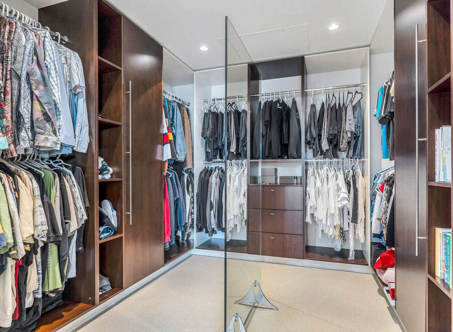 This luxurious walk-in closet boasts ample space with custom built-in cabinetry, including shelves and hanging rods for clothing storage.