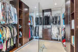 This luxurious walk-in closet boasts ample space with custom built-in cabinetry, including shelves and hanging rods for clothing storage.