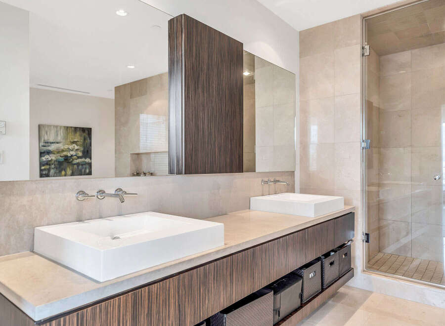 This luxurious bathroom boasts dual vanities with sleek, modern sinks and ample storage space.