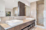 This luxurious bathroom boasts dual vanities with sleek, modern sinks and ample storage space.