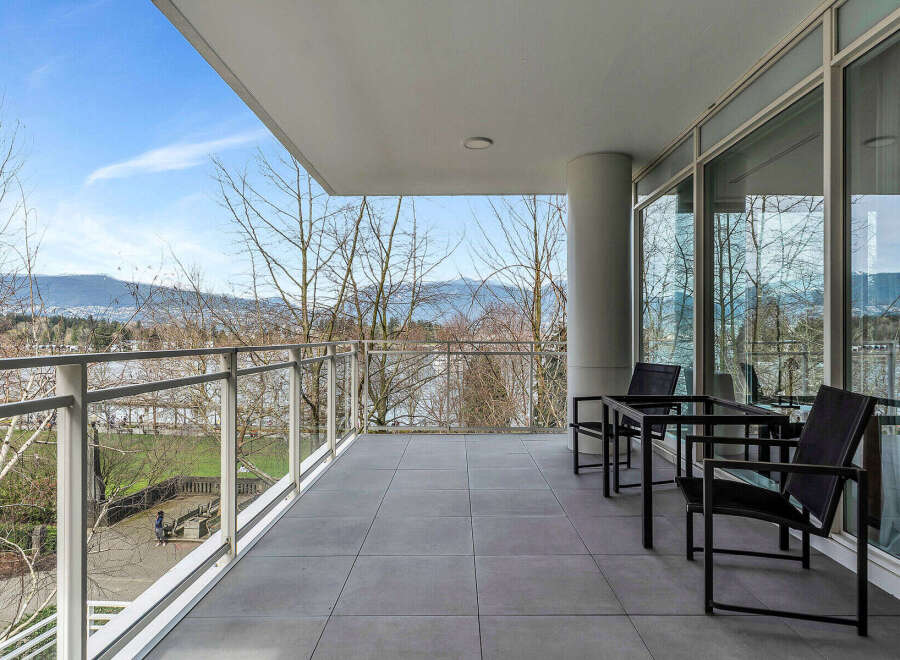 This luxurious condo boasts a spacious balcony with breathtaking views of the mountains and water.