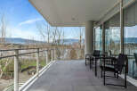 This luxurious condo boasts a spacious balcony with breathtaking views of the mountains and water.