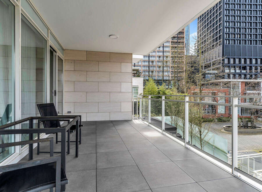 This luxurious condo boasts a spacious balcony with modern glass railings, offering stunning city views.