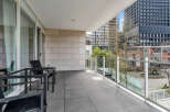 This luxurious condo boasts a spacious balcony with modern glass railings, offering stunning city views.