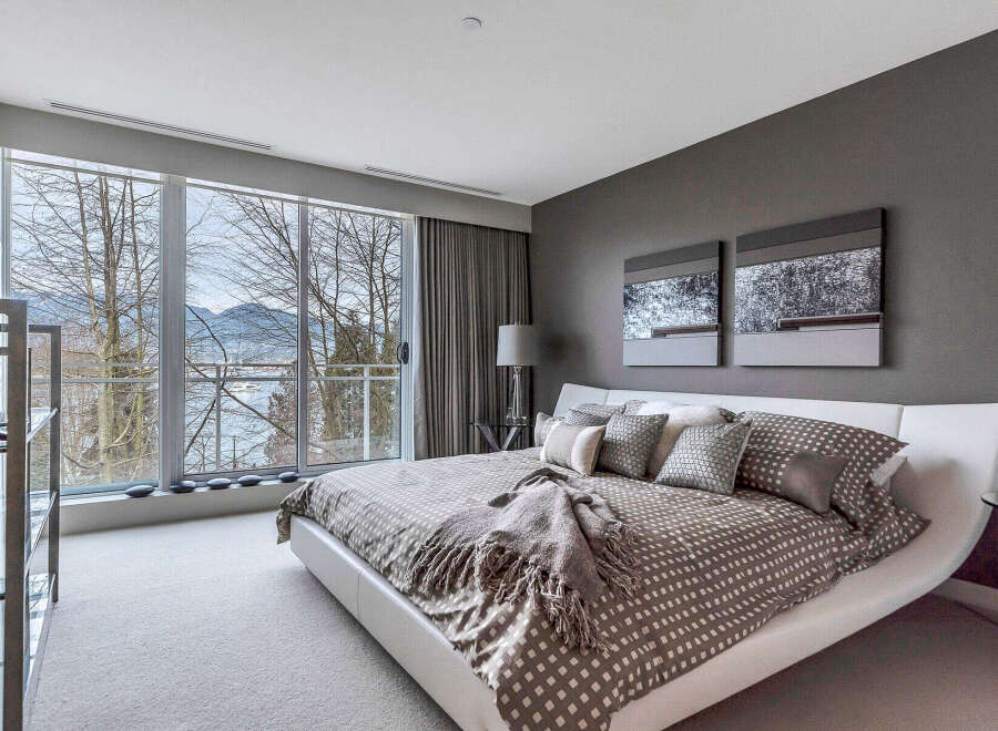 This luxurious bedroom boasts a stunning view of the water and mountains through large sliding glass doors.