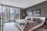 This luxurious bedroom boasts a stunning view of the water and mountains through large sliding glass doors.