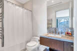This modern bathroom boasts a sleek design with granite countertops, a contemporary vanity, and a spacious shower with a white curtain.
