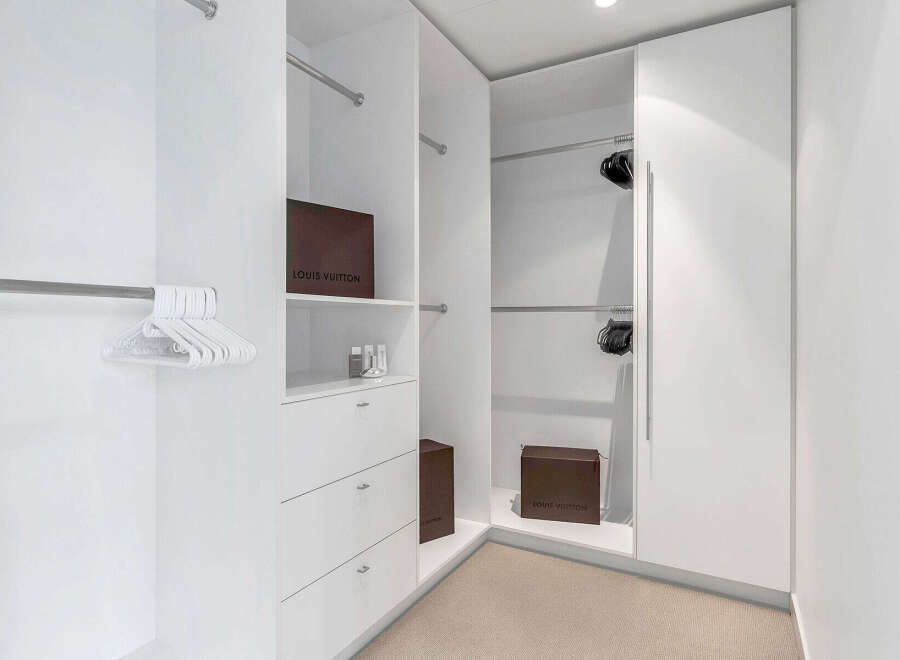 This luxurious walk-in closet boasts ample hanging space, complemented by built-in drawers and shelves for organized storage.