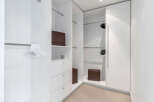 This luxurious walk-in closet boasts ample hanging space, complemented by built-in drawers and shelves for organized storage.