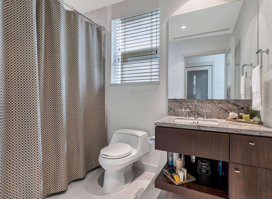This stunning bathroom boasts a modern design with a spacious vanity featuring granite countertops and ample storage.