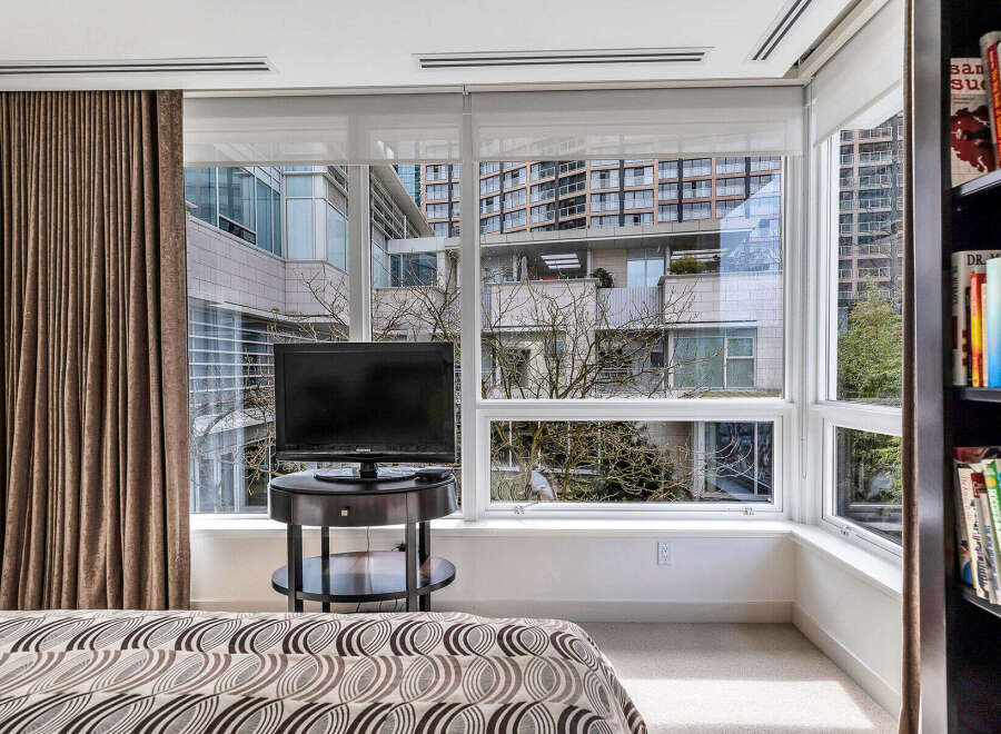 Bright bedroom with floor-to-ceiling windows offering stunning city views.