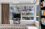 Bright bedroom with floor-to-ceiling windows offering stunning city views.