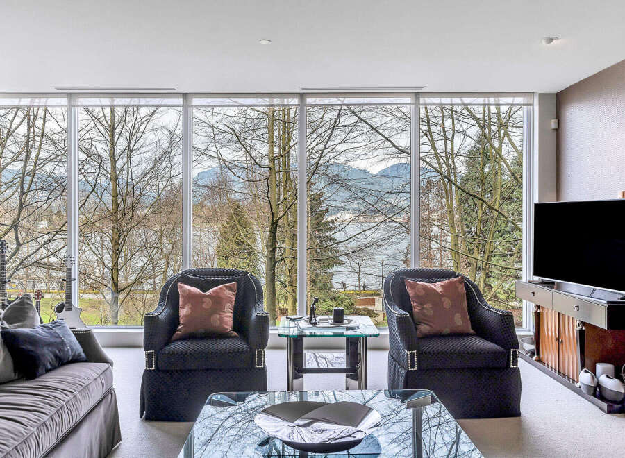 This luxurious living room boasts floor-to-ceiling windows showcasing breathtaking views of nature and water.