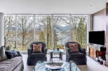 This luxurious living room boasts floor-to-ceiling windows showcasing breathtaking views of nature and water.
