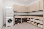 This laundry room boasts a modern design with beige cabinets, a dark countertop, and Miele washer and dryer.