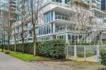 This modern building features a sleek design with floor-to-ceiling windows, private balconies, and a well-maintained landscaped area.