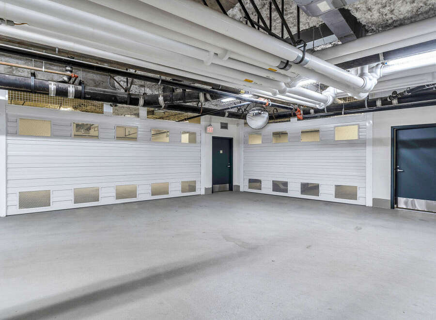 This spacious parking garage boasts two large, white roll-up doors, each featuring multiple windows for ample natural light and ventilation.