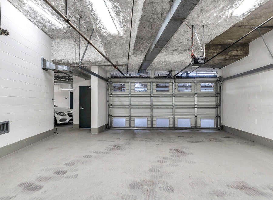 This spacious garage boasts high ceilings, ample space for parking, and modern finishes.