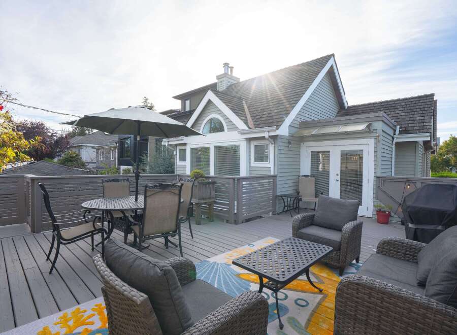This charming home boasts a spacious deck perfect for outdoor entertaining, complete with comfortable wicker furniture and a dining set.