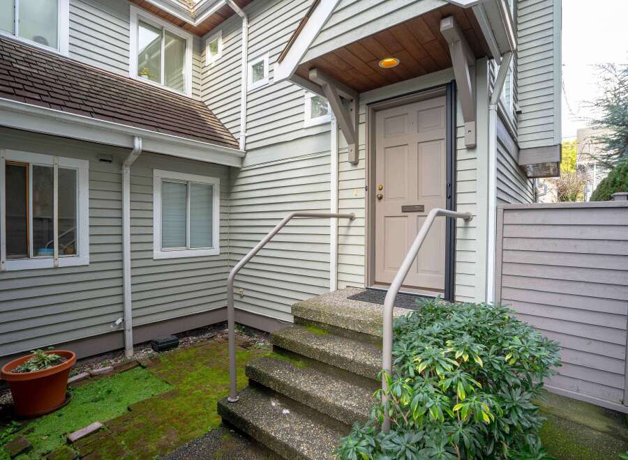 This charming house boasts a welcoming front entrance with a covered porch and steps leading to a light taupe door.