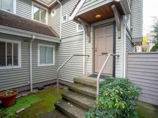 This charming house boasts a welcoming front entrance with a covered porch and steps leading to a light taupe door.