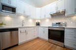 This stunning kitchen boasts modern white shaker cabinets, complemented by stainless steel appliances and sleek hardware.