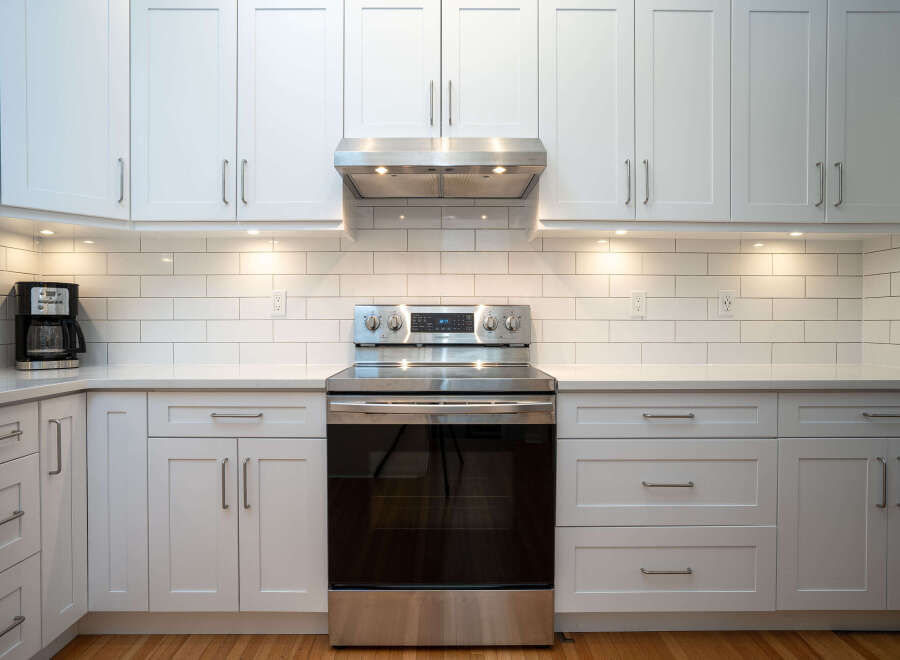 This stunning kitchen boasts a sleek, modern design with white shaker cabinets and subway tile backsplash.