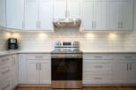 This stunning kitchen boasts a sleek, modern design with white shaker cabinets and subway tile backsplash.