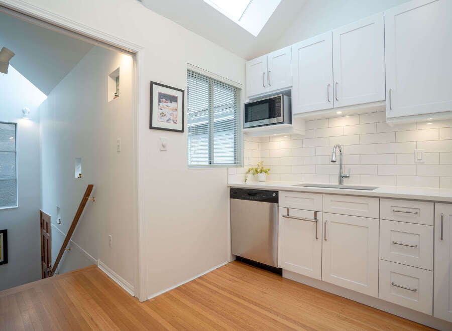 This bright and airy kitchen boasts modern white shaker cabinets, stainless steel appliances, and sleek countertops.