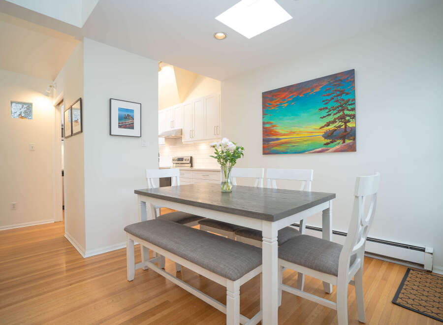 This bright and airy dining area features a grey table with white chairs and bench, perfect for family meals.