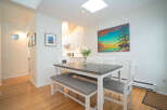 This bright and airy dining area features a grey table with white chairs and bench, perfect for family meals.