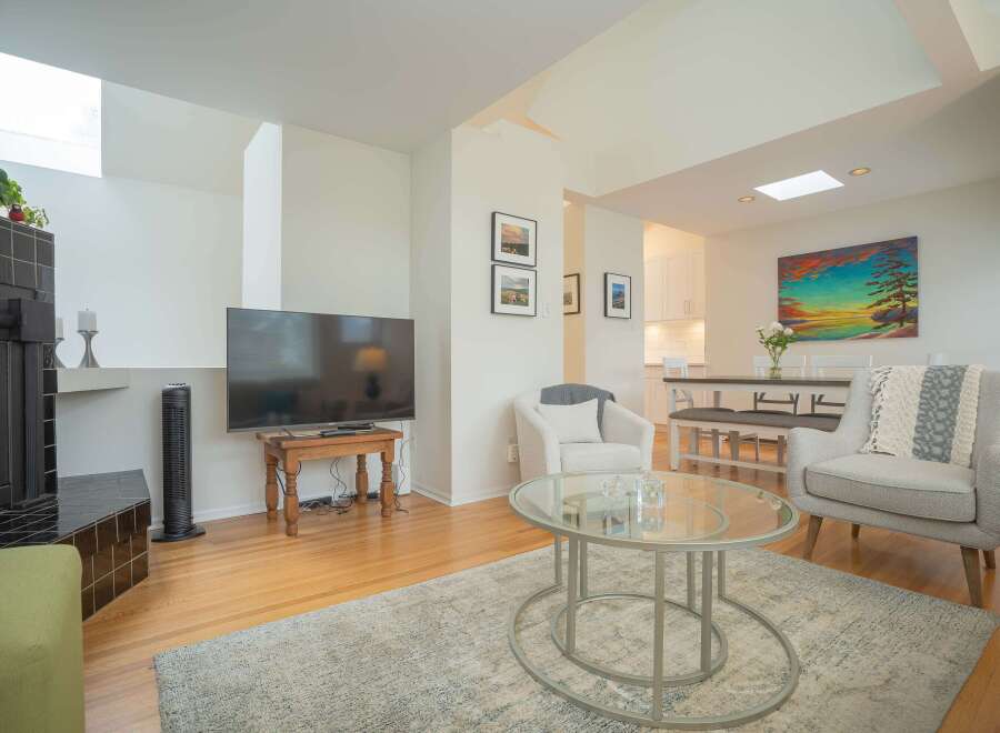 Bright and airy living room with hardwood floors, featuring a cozy seating area with two armchairs and a glass coffee table.