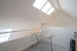 This bright loft-style room features a glass desk perfect for a home office, complemented by a stylish desk lamp.