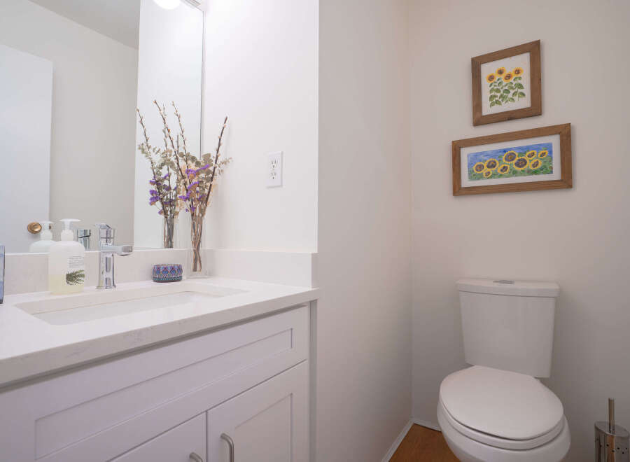 This stylish bathroom boasts a modern white vanity with a quartz countertop, complemented by a sleek chrome faucet and tasteful floral decor.