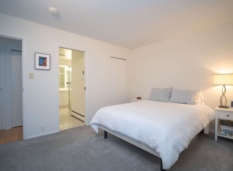 This bright and airy bedroom features a comfortable queen-sized bed with crisp white linens, complemented by a neutral color palette.