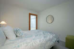 This bright bedroom features a comfortable bed with a leaf patterned duvet, plush pillows, and a bedside lamp.