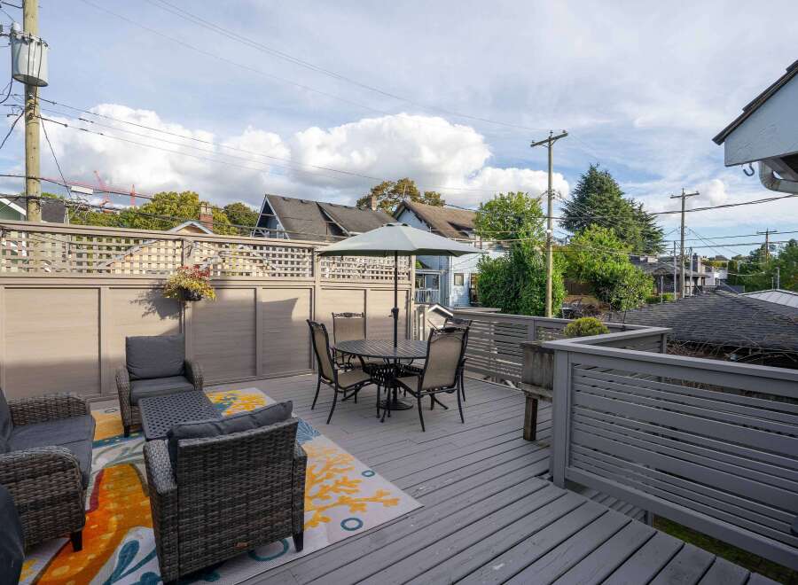 This charming home boasts a spacious deck perfect for outdoor entertaining, complete with comfortable seating and a dining area.