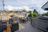 This charming home boasts a spacious deck perfect for outdoor entertaining, complete with comfortable seating and a dining area.