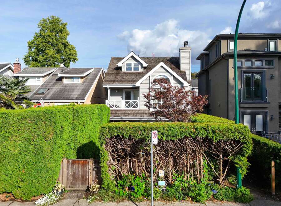 Charming house nestled amongst lush greenery, featuring a unique architectural design with a dormer window and a balcony.