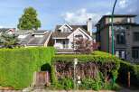 Charming house nestled amongst lush greenery, featuring a unique architectural design with a dormer window and a balcony.
