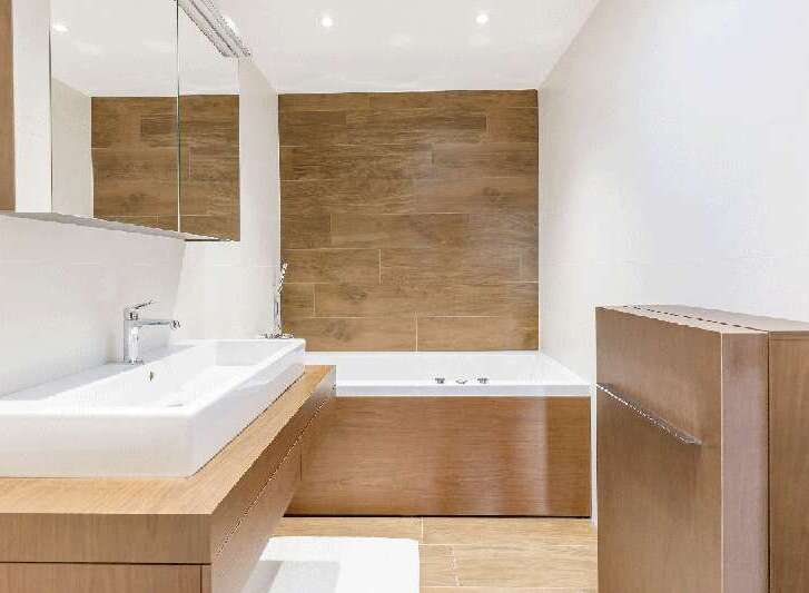 This modern bathroom features a sleek design with a wooden accent wall and cabinetry, creating a warm and inviting atmosphere.